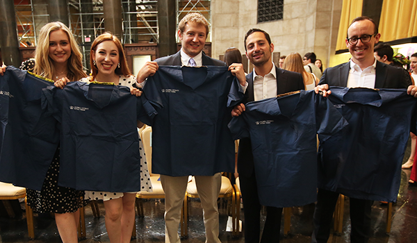 Students celebrate Postbac Class Day and hold up Columbia scrubs.