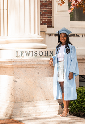 Serengeti Timungwa poses in front of Lewisohn Hall in her graduation cap and gown