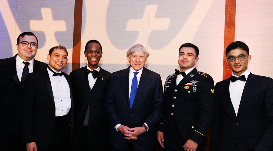 Five attendees to the Military Ball, including President Lee C. Bollinger, pose in front of an image of the Columbia crown