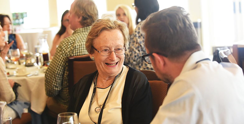 An alumna laughs during a conversation with a fellow alum