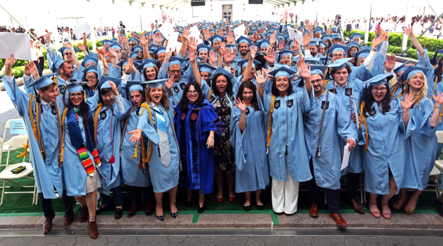 Hundreds of GS graduates in blue gowns celebrate under the graduation ceremony tent