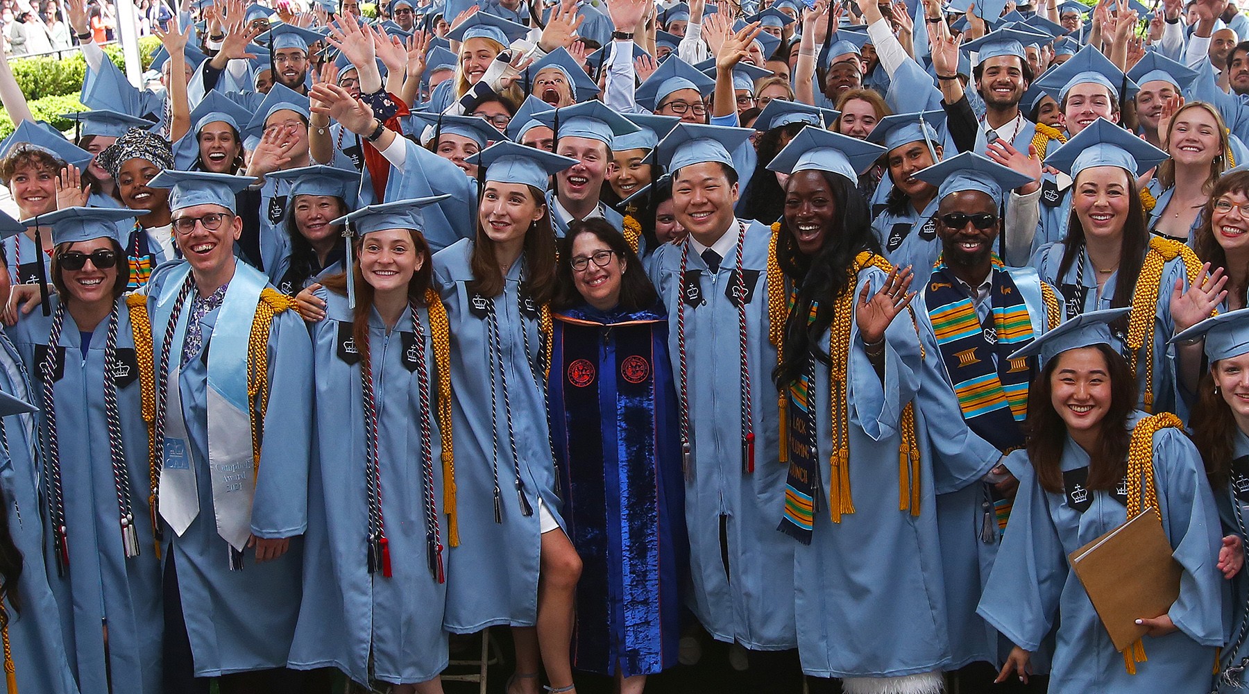 Hundreds of GS graduates in blue gowns celebrate under the graduation ceremony tent.