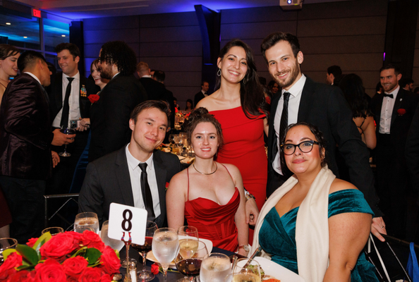 Five students smile at a table 