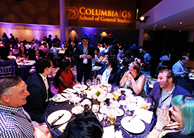 Guests converse at the annual GS Reunion Dinner Shot of several tables at the annual GS Reunion Dinner with the 75th anniversary logo projected onto the wall in the background