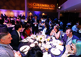 Shot of several tables at the annual GS Reunion Dinner with the 75th anniversary logo projected onto the wall in the background