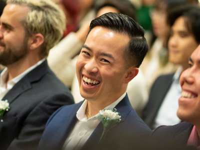 Attendee at the February Student graduation reception, seated and laughing during reception's remarks