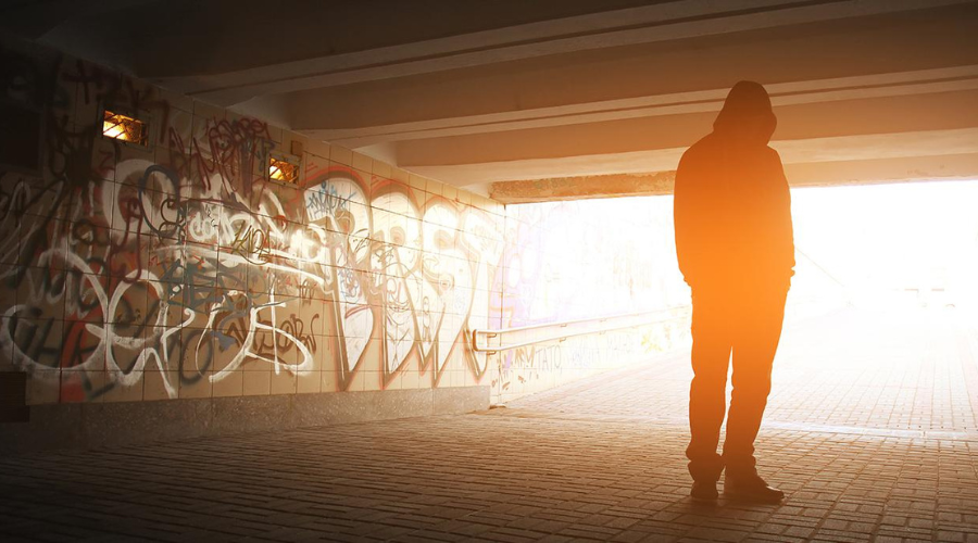 Image of a person standing in an alleyway with extreme lighting contrasts; sourced from the original article from Columbia Mailman 