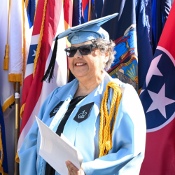 Columbia GS graduate Lisa Delgado Smith '25GS poses in front of flags at Class Day.