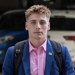 Kolin Krizan heashot in navy blazer and pink button up