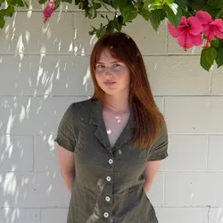 Ashley Zanelli in front of a wall and pink flowers