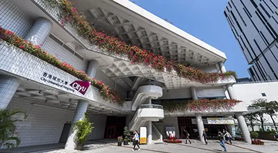 People walking in front of a white building on the campus of City University of Hong Kong