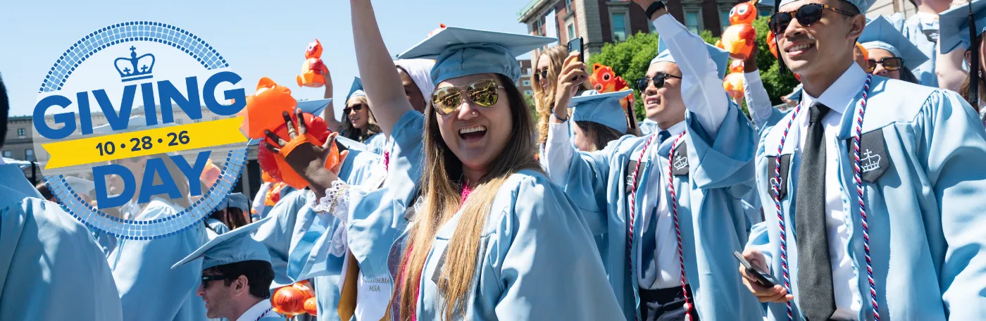 Columbia GS graduates at University Commencement, Giving Day logo in the foreground.