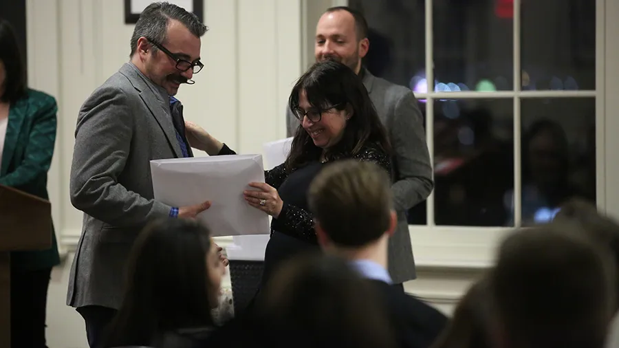 Dean Rosen-Metsch greets a student as he collects his Honor Society certificate.