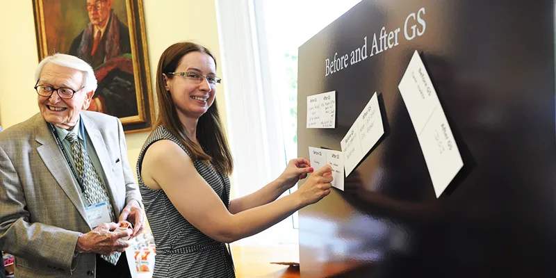 Two alumni post their "GS stories" to a board