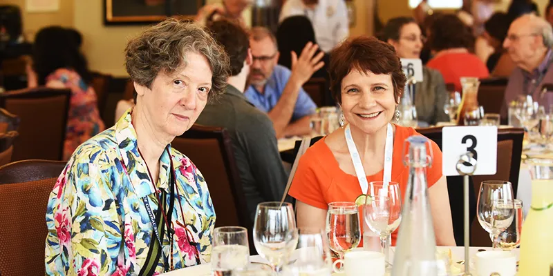 Two women smiling at their table during the Dean's Luncheon