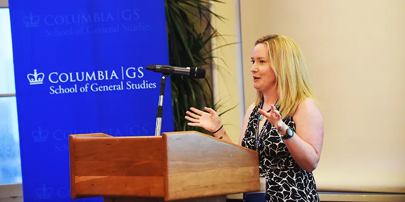 Kirsty Jardine speaks to dinner attendees with a Columbia GS stanchion in the background 