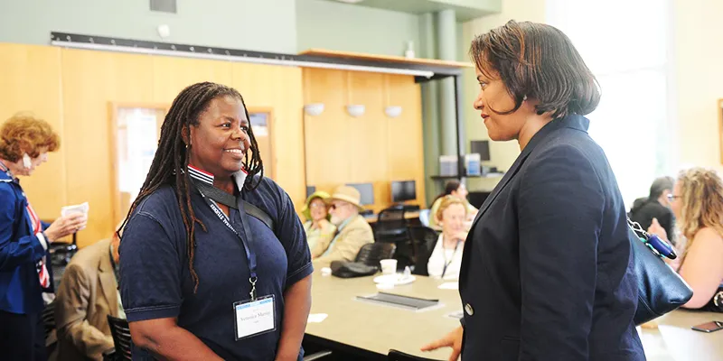 Two women share a conversation in the GS Lounge