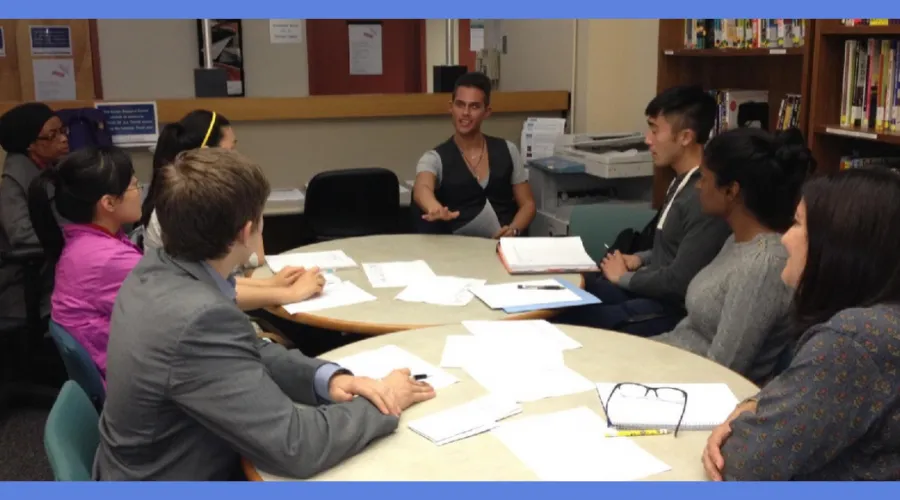 Alumni and students gather around a table to discuss employment opportunities in the field of consulting