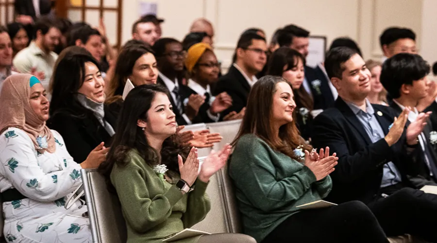 Graduates and guests seated in the audience clapping