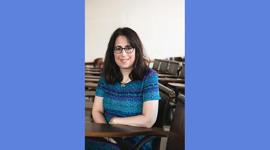 Dean Lisa Rosen-Metsch sitting at a wooden desk in a classroom
