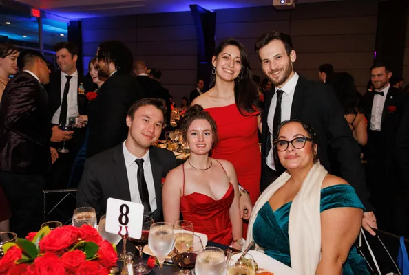 Five students smile at a table 