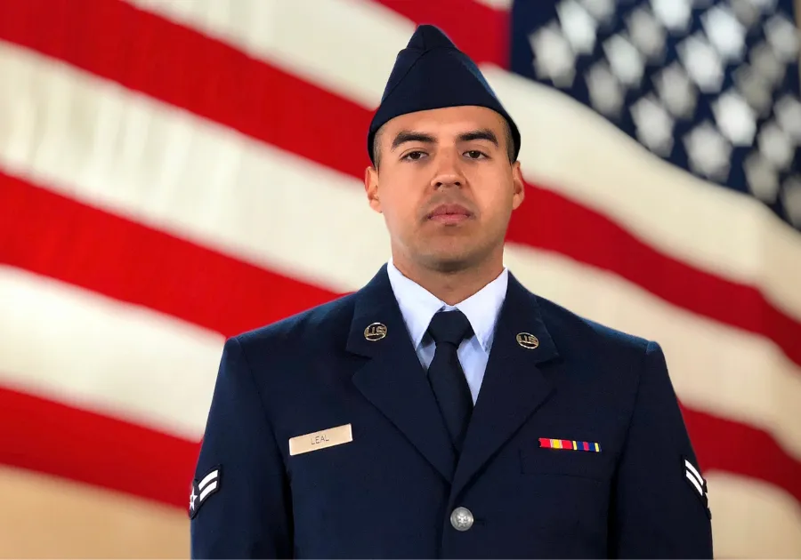 Brian Leal '25GS in a military uniform standing in front of an American flag.