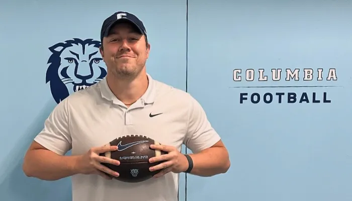David Garland '26GS, holding a football with the Columbia football team logo in the background