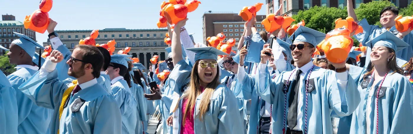 Graduates at the 2023 University Commencement ceremony, holding GS owl ballons